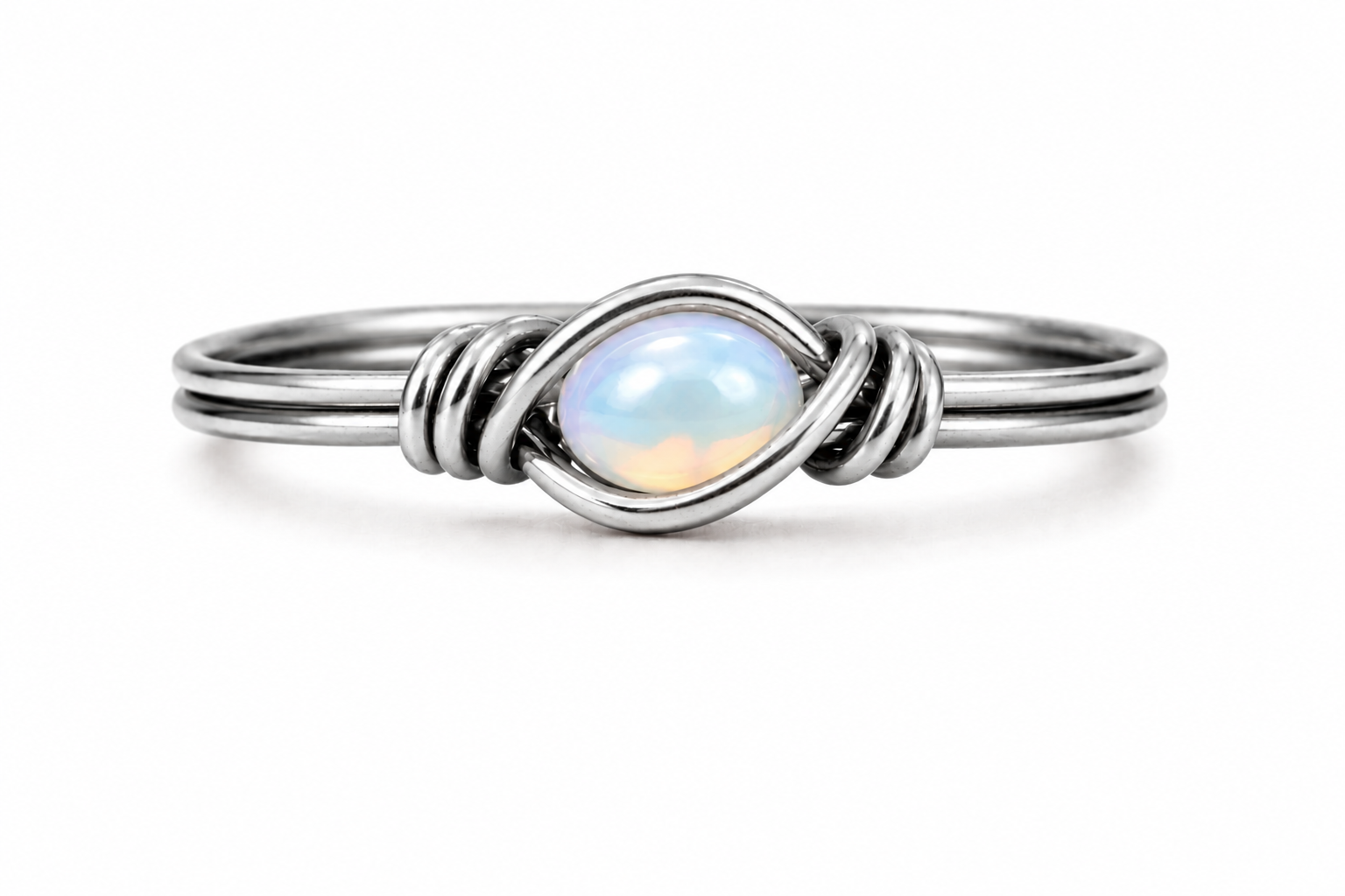 A silver ring featuring a central oval cabochon opal with iridescent blue, white, and soft peach hues, set in a twisted wrap design on a clean white background.